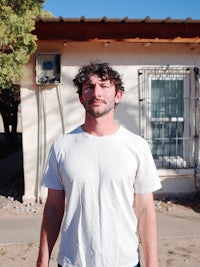 a man standing in front of a house with a skateboard