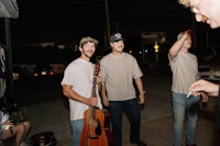 a group of men standing in a street with guitars