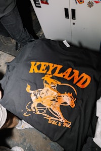 a man is holding a t - shirt that says keyland