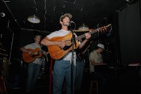 a man playing an acoustic guitar in front of a microphone