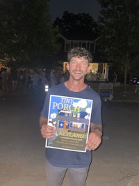 a man holding a book in front of a street