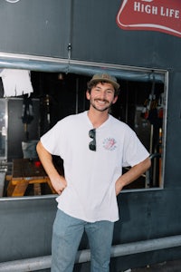 a man in a white t - shirt standing in front of a building