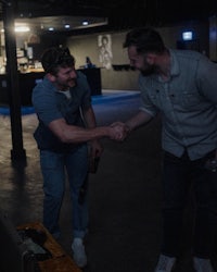 two men shaking hands in a dark room